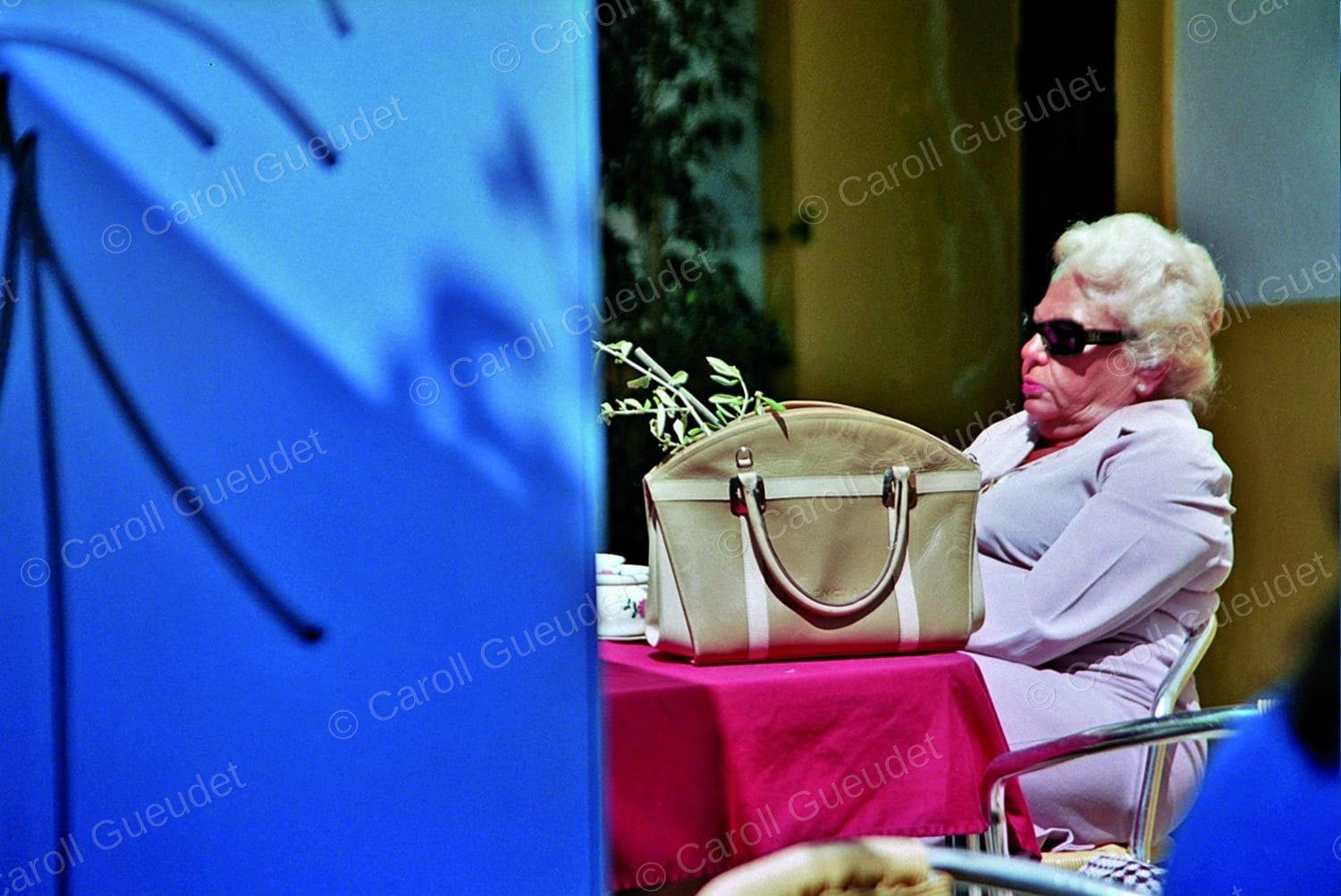 Photographie de Caroll Gueudet : une femme aux lunettes de soleil, attablée